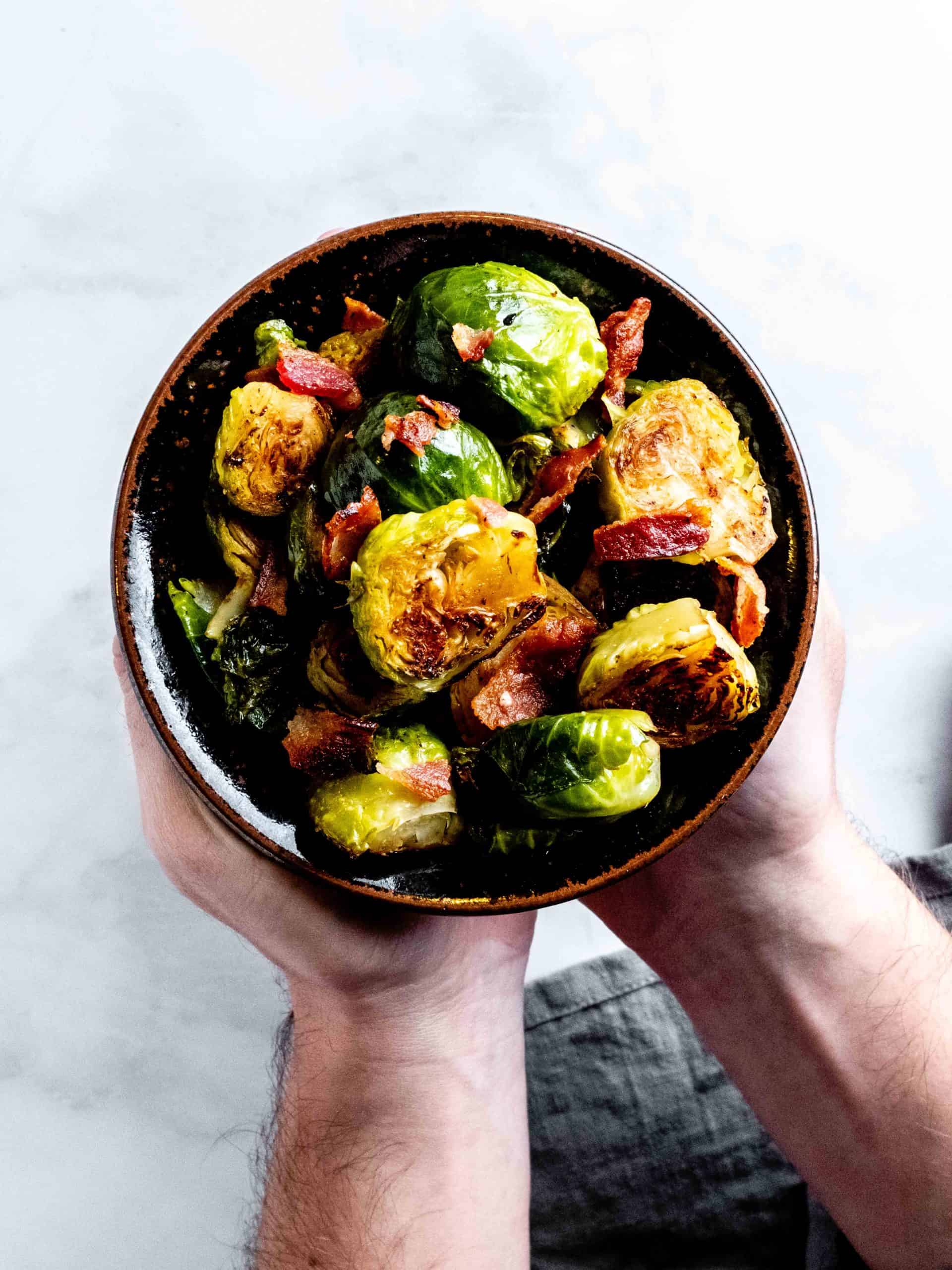 holding a bowl of sauteed brussels sprouts