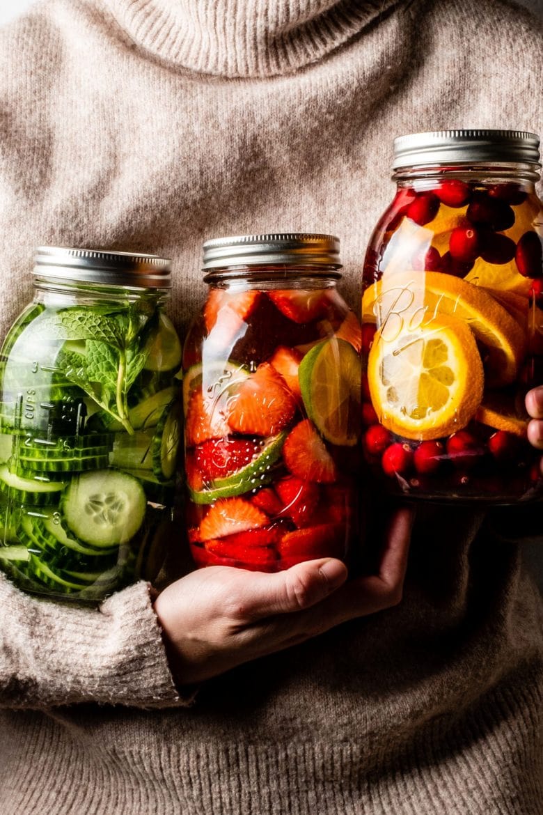 holding three jars of fruit infused vodka