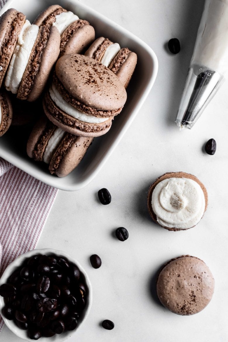 piping kahlua buttercream on chocolate macarons