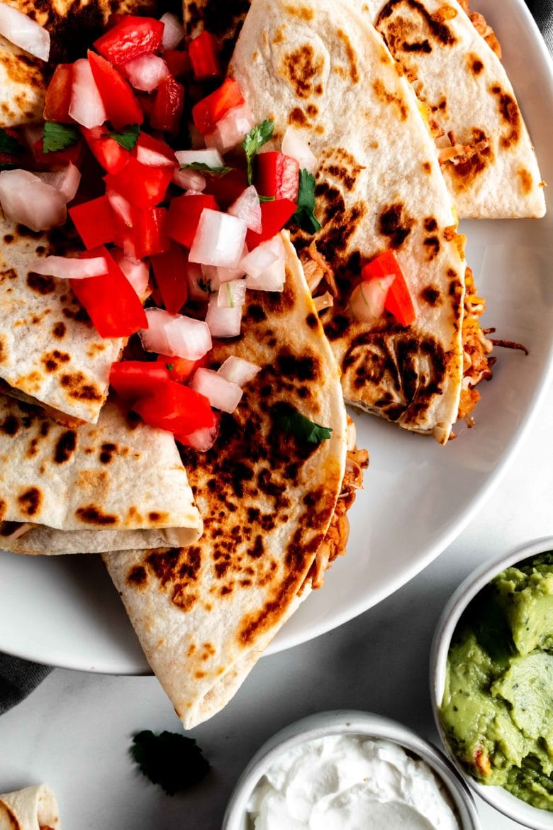 quesadillas on a plate with salsa, guacamole and sour cream