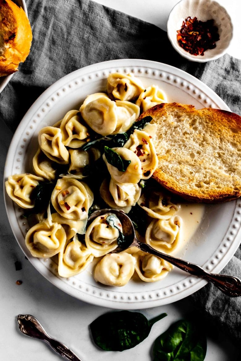 plate of tortellini with white wine cream sauce, toasted bread and spinach