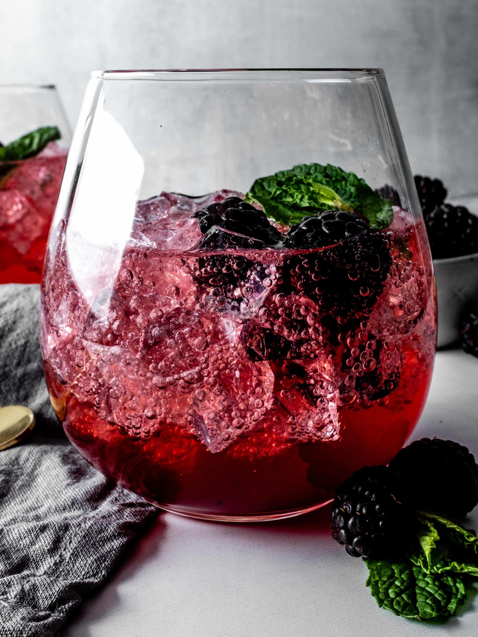 glass of vanilla blackberry shrub with ice and seltzer