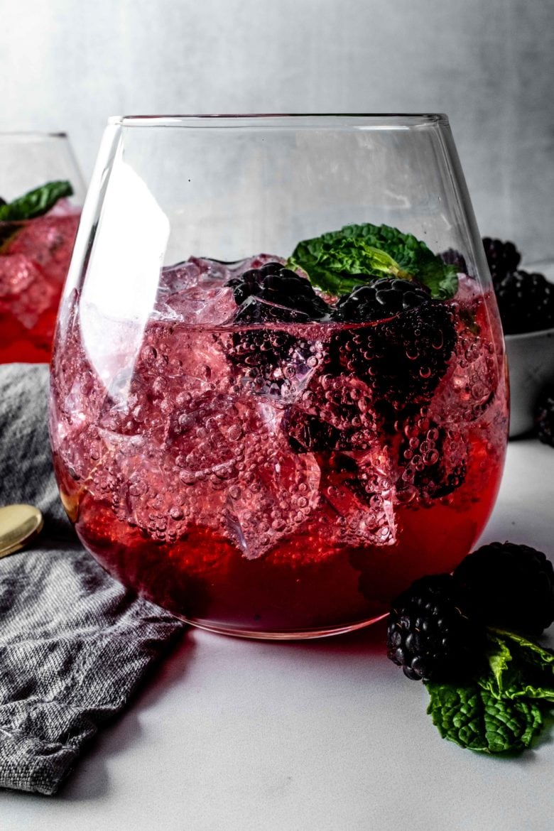 glass of vanilla blackberry shrub with ice and seltzer