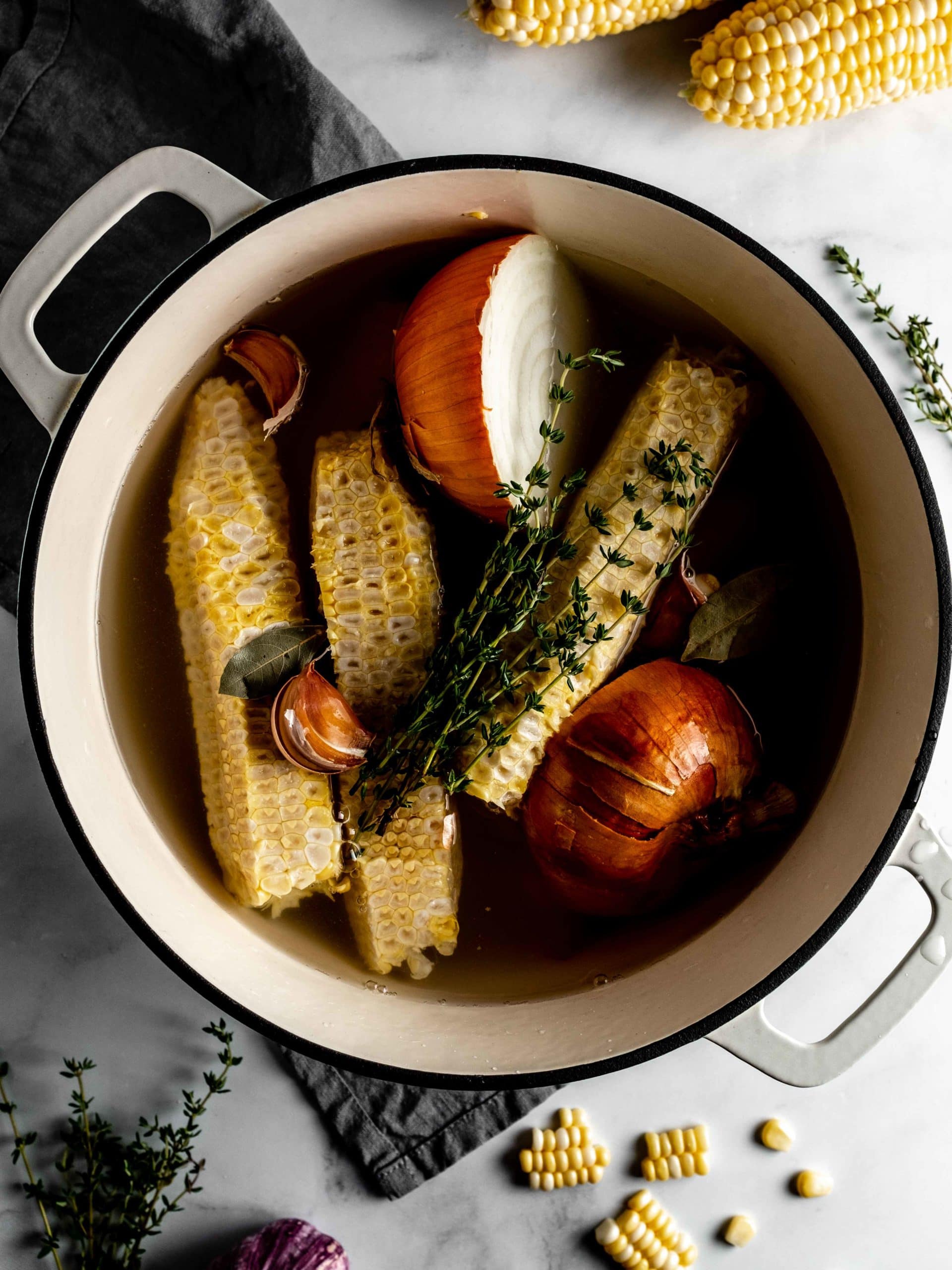 pot with corn cobs, onion and thyme