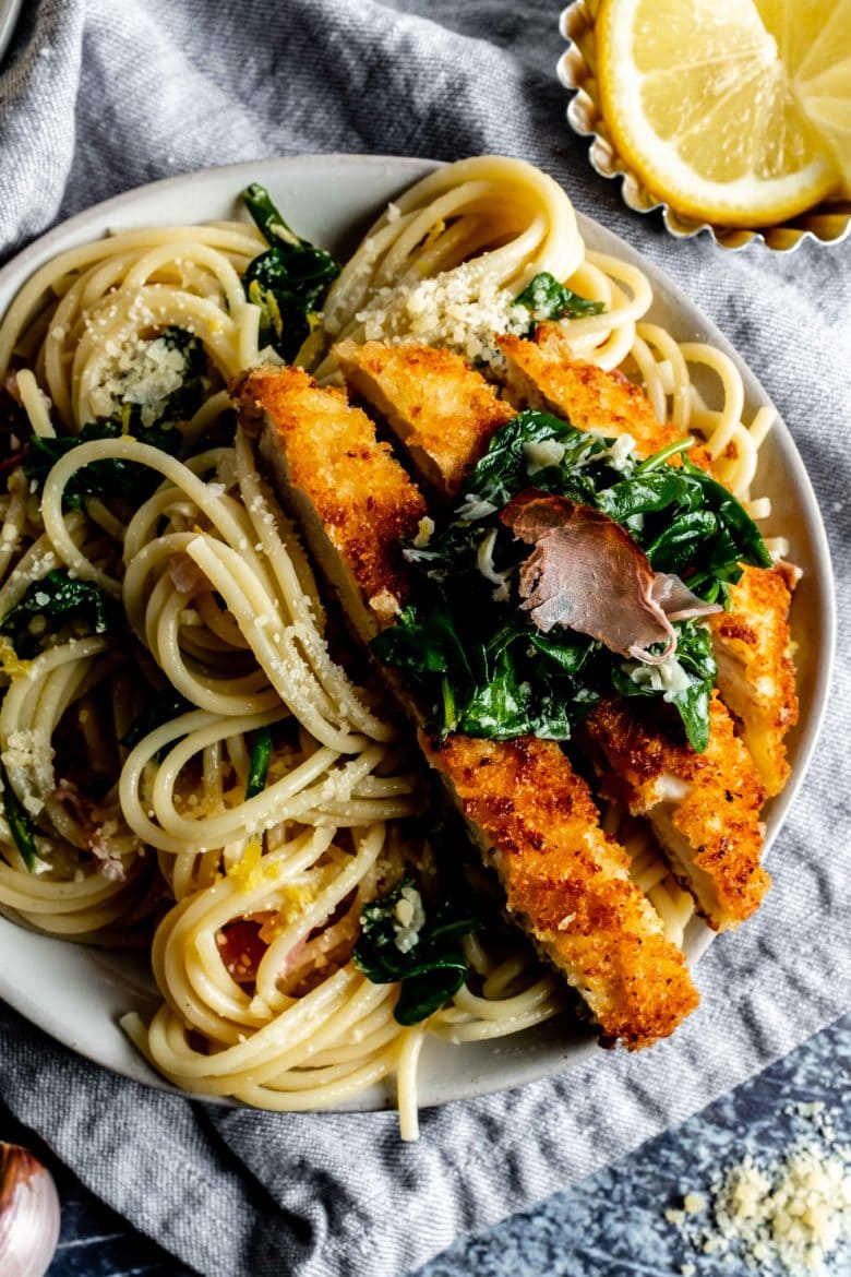 plate of lemon pasta with slices of parmesan crusted chicken