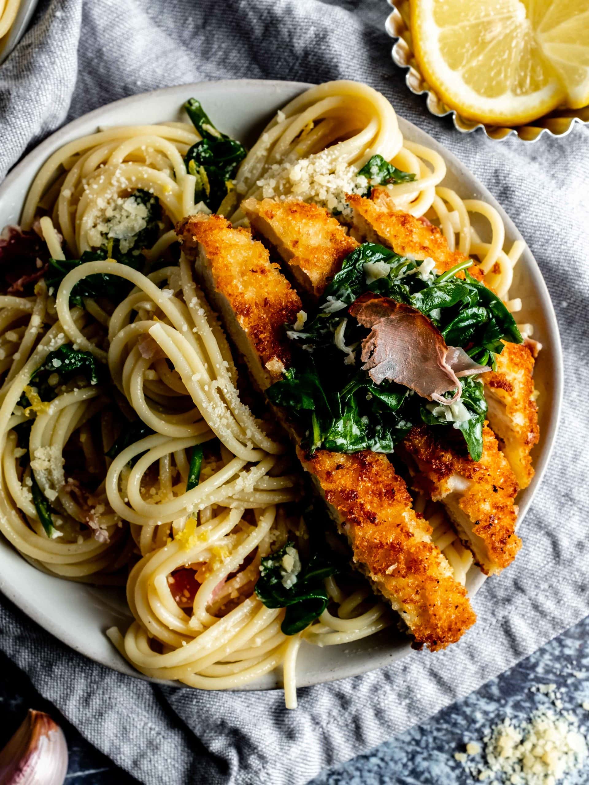 plate of lemon pasta with slices of parmesan crusted chicken