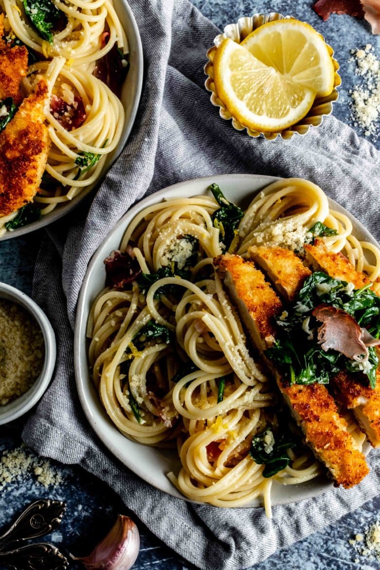 two plates of lemon pasta with chicken, arugula and prosciutto
