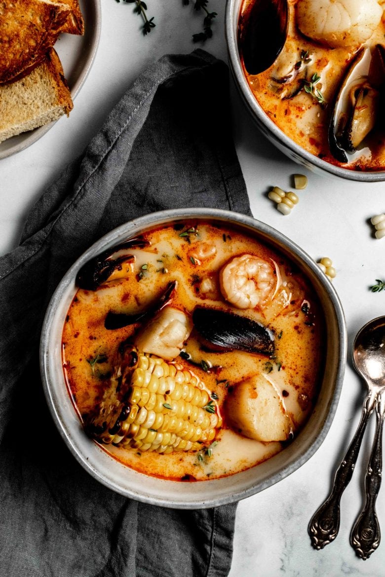 bowl of soup with corn on the cob, mussels, scallops and shrimp