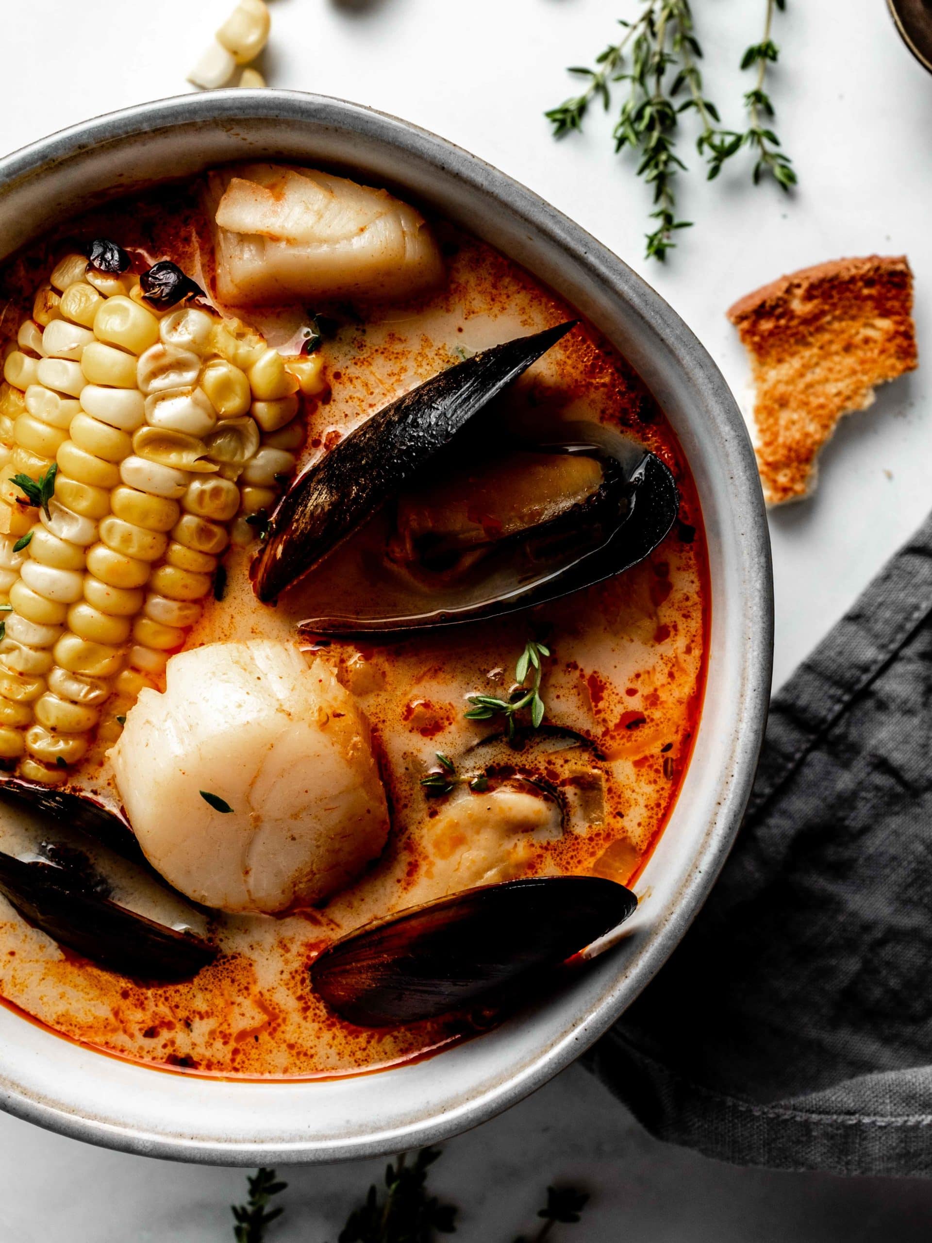 bowl of soup with corn on the cob, mussels, scallops and shrimp