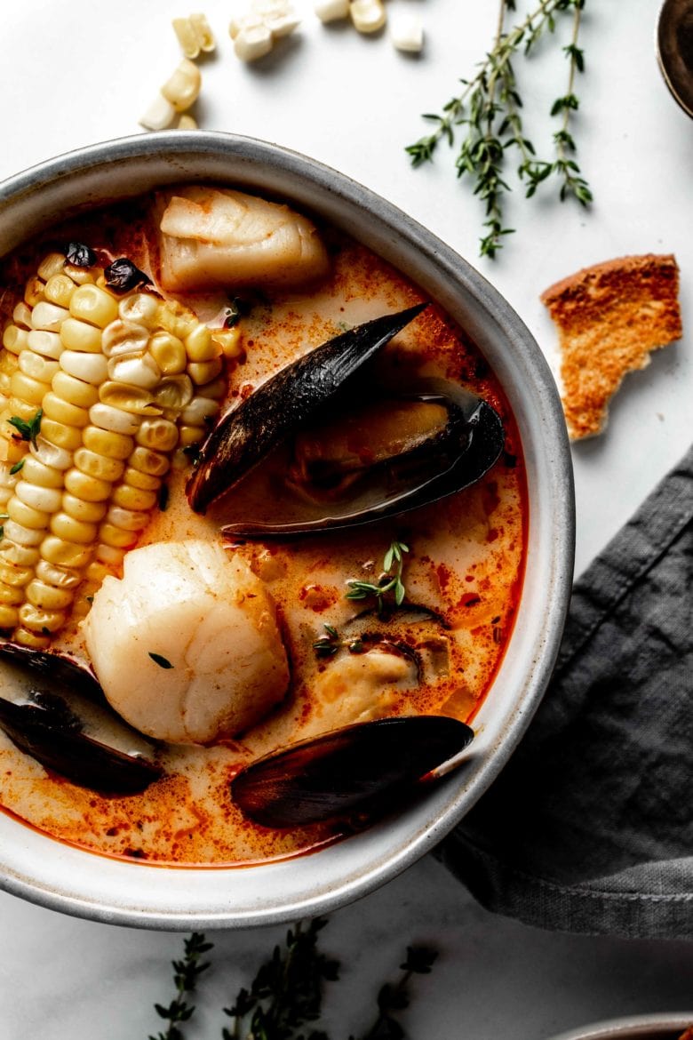 bowl of soup with corn on the cob, mussels, scallops and shrimp