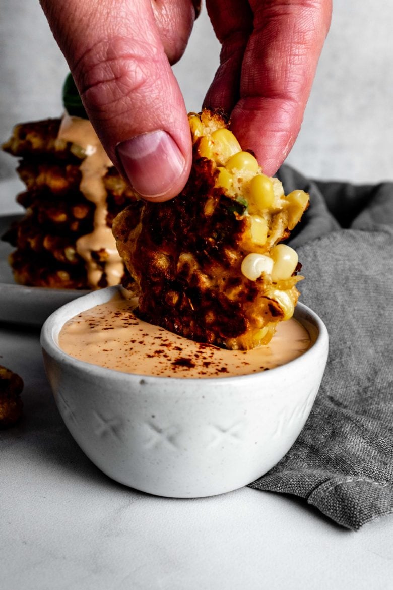 dipping sweet corn fritter into chipotle sauce