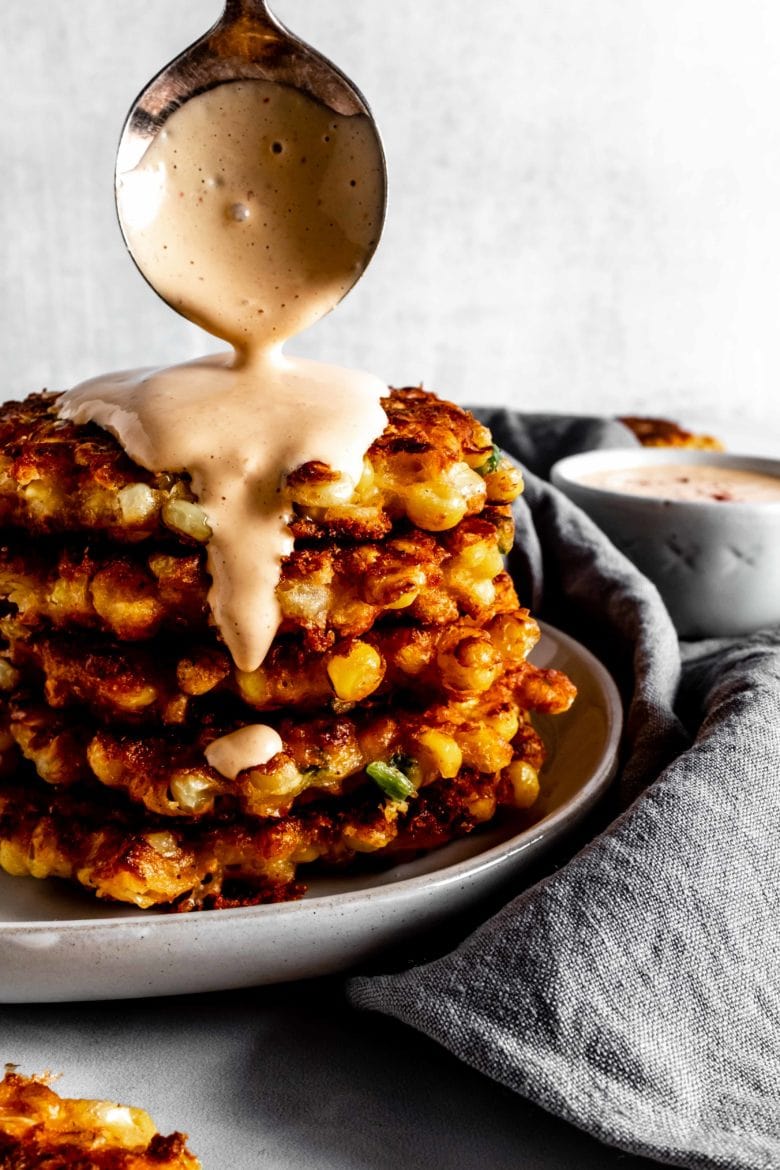 stack of mexican street corn fritters with a drizzle of chipotle sauce