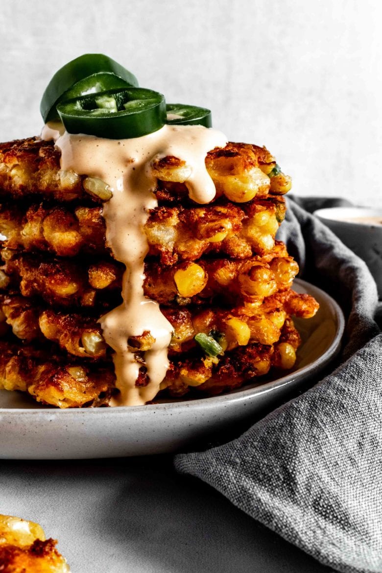 stack of corn fritters with chipotle sauce and fresh jalapenos