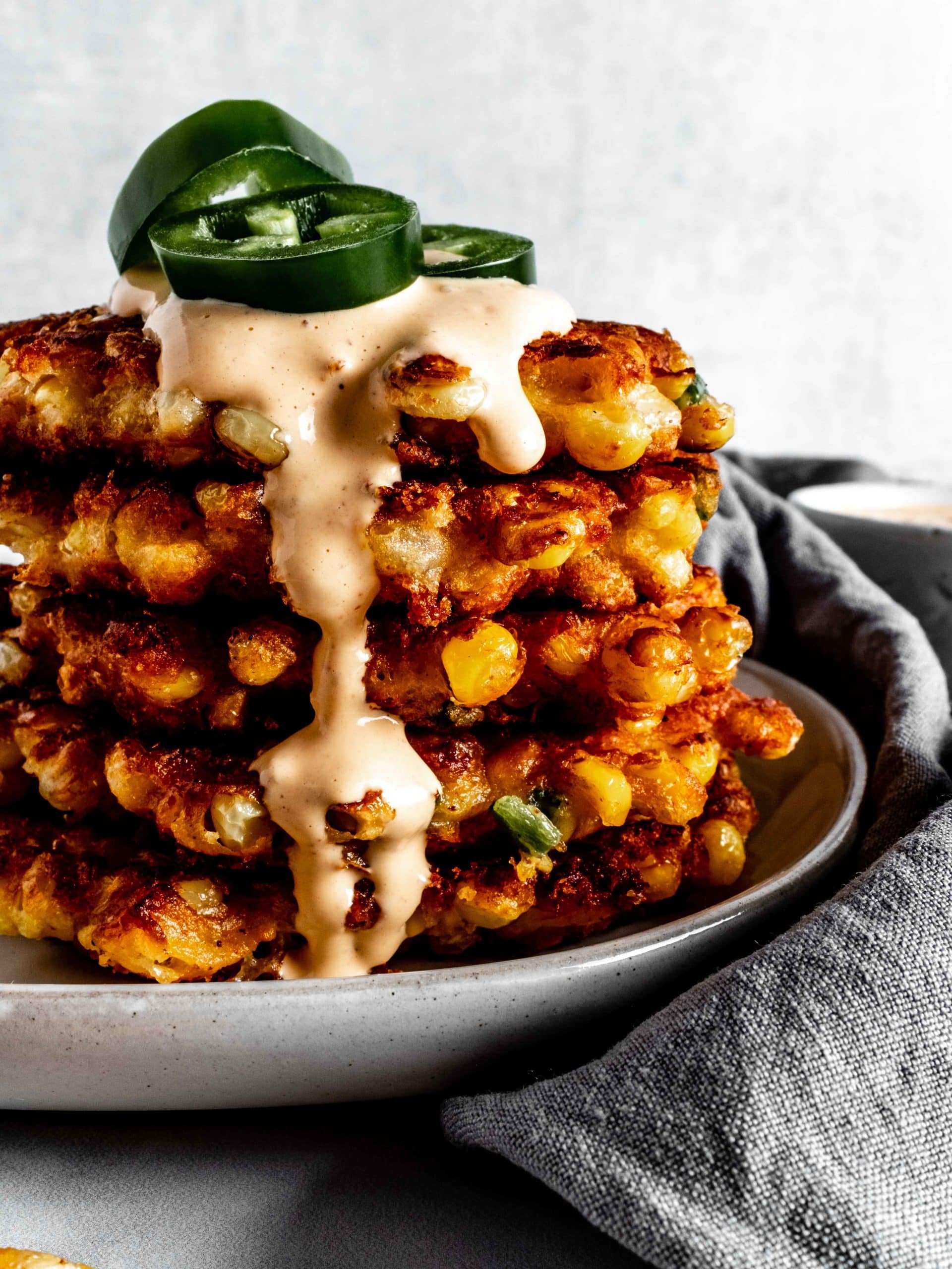 stack of corn fritters with chipotle sauce and fresh jalapenos