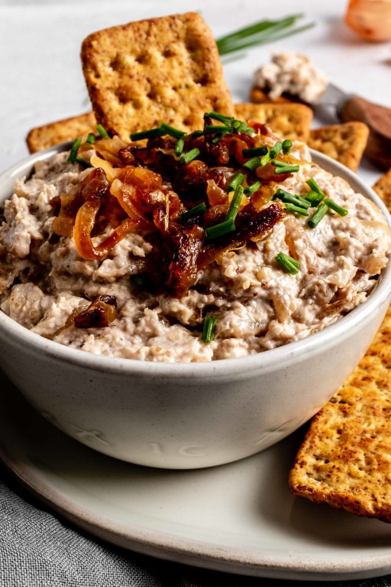 dipping cracker into walnut and caramelized onion dip