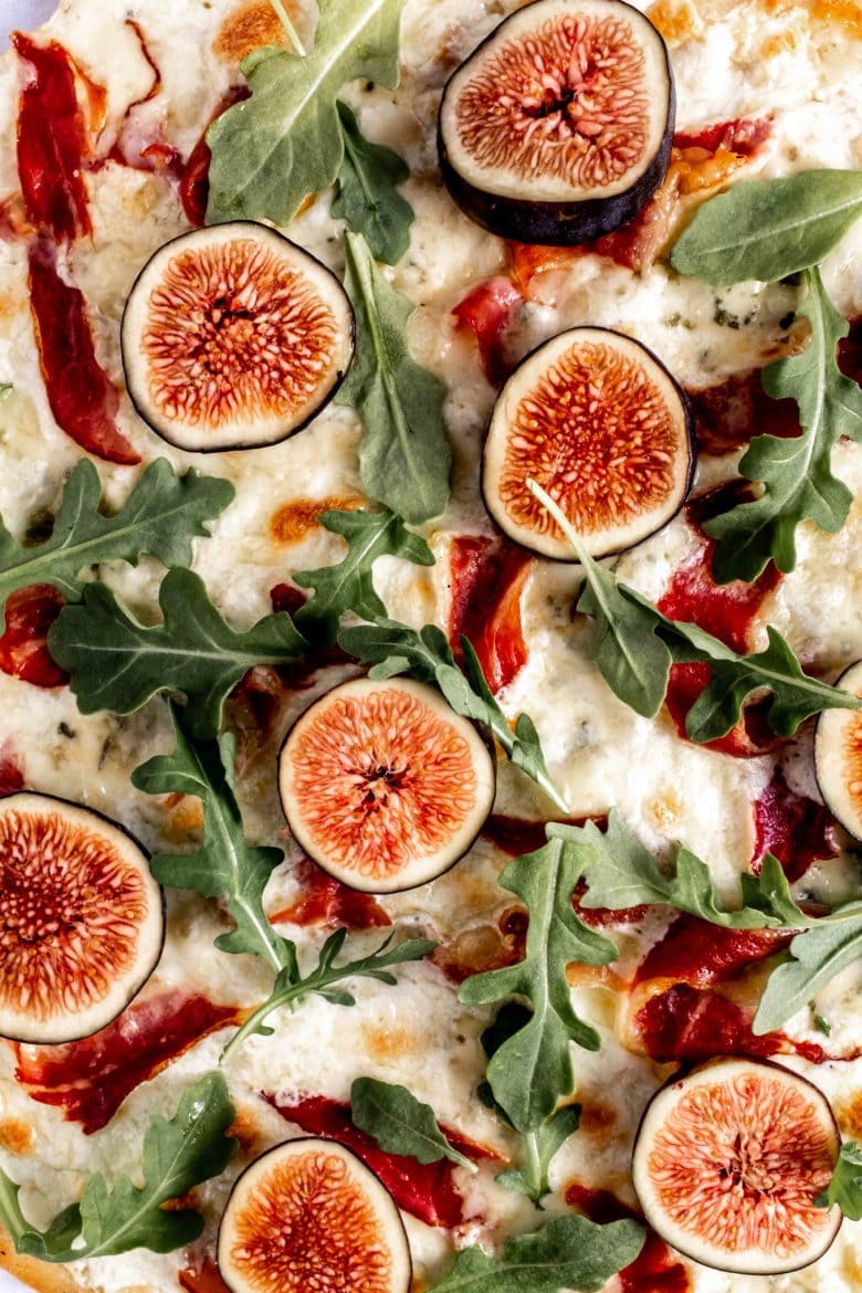 close up of pizza with fresh figs and arugula