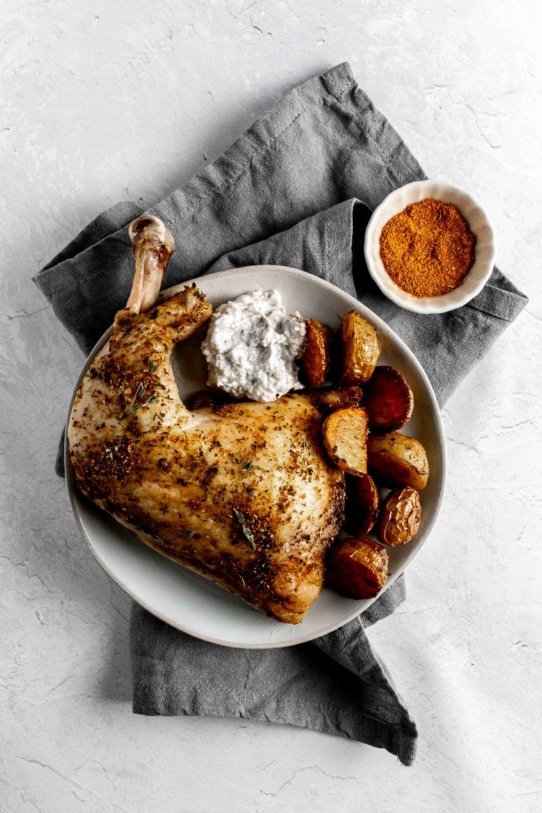 plate with chicken leg quarter, potatoes and yogurt sauce