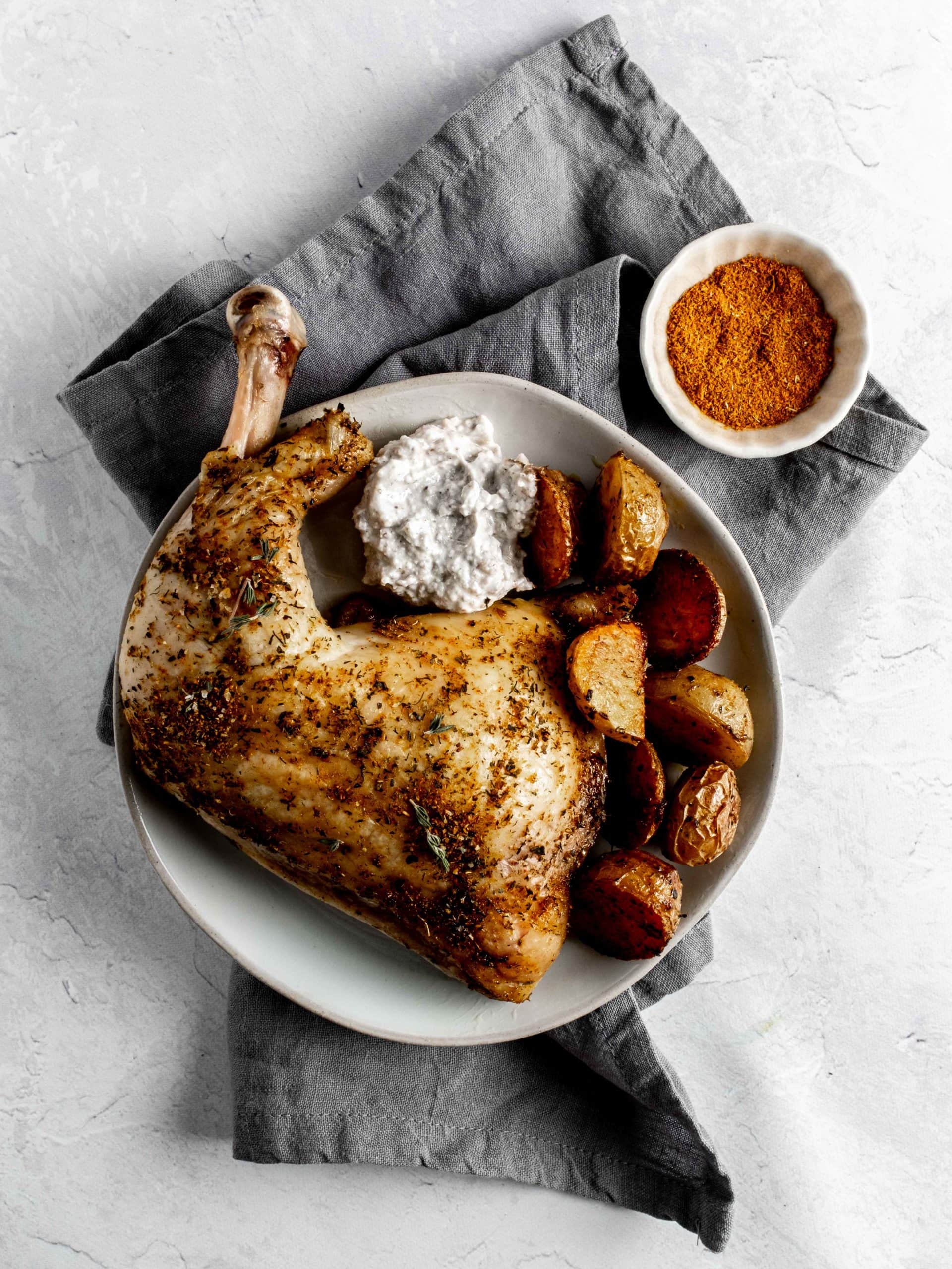 plate with chicken leg quarter, potatoes and yogurt sauce