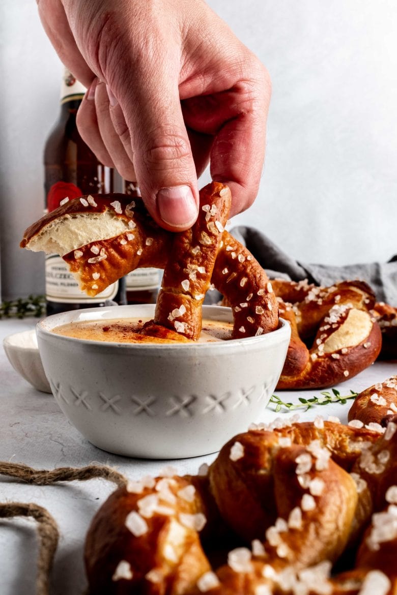 dipping soft pretzel into beer cheese sauce