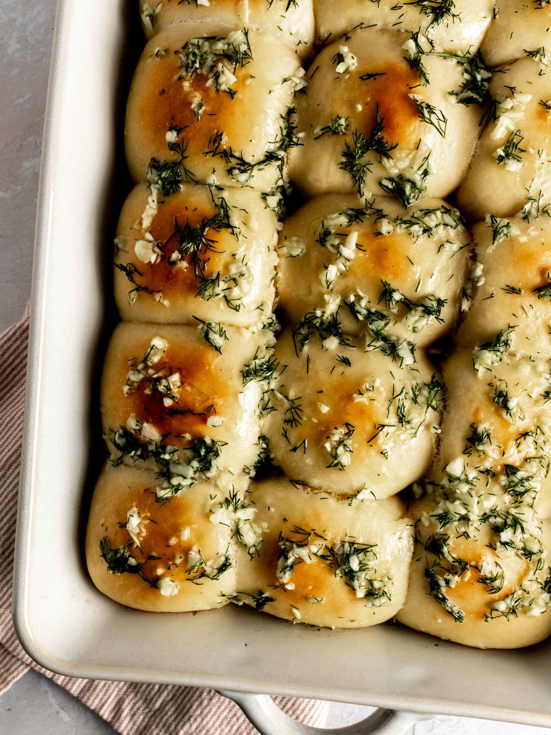 baking dish with pampushky covered in garlic and dill