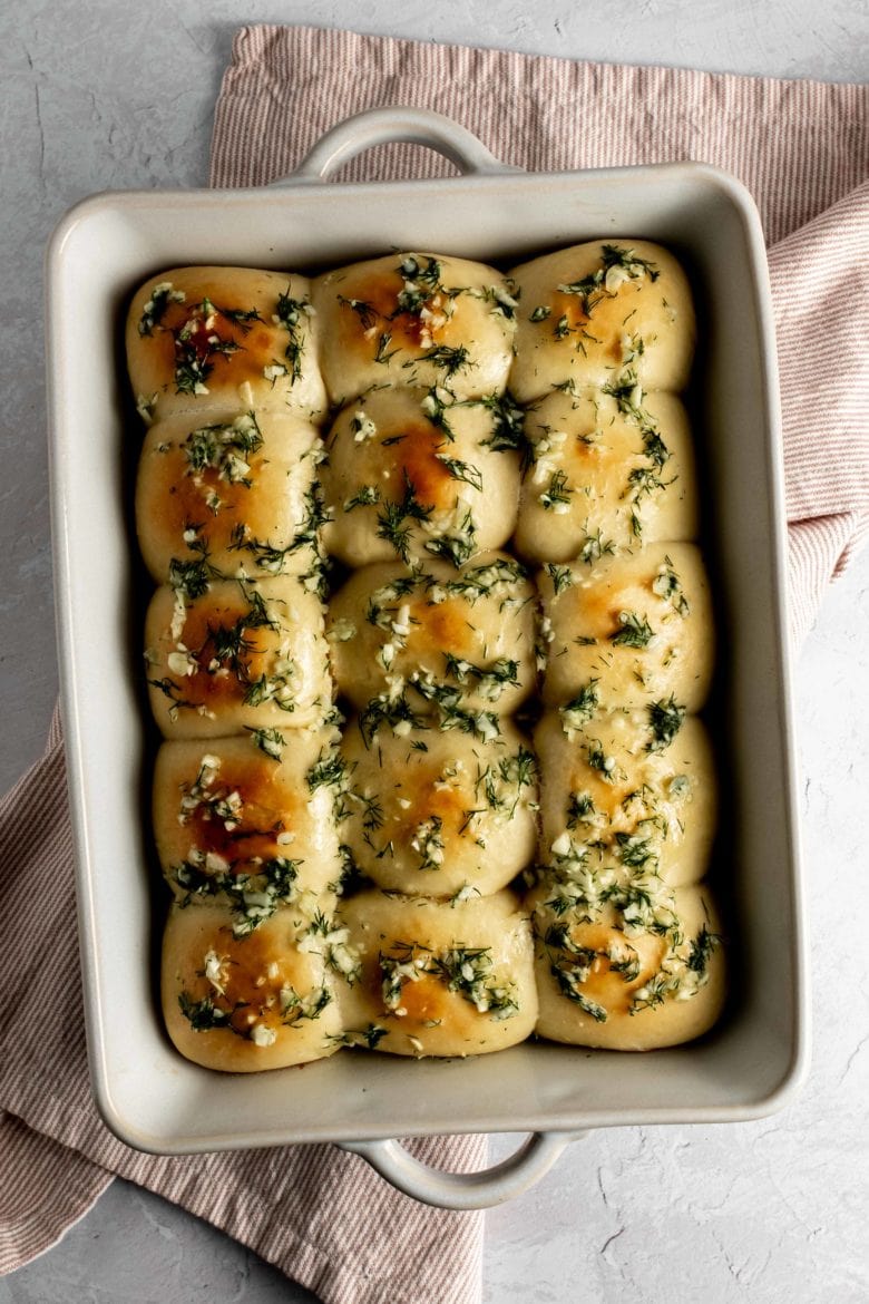 baking dish with pampushky covered in garlic and dill