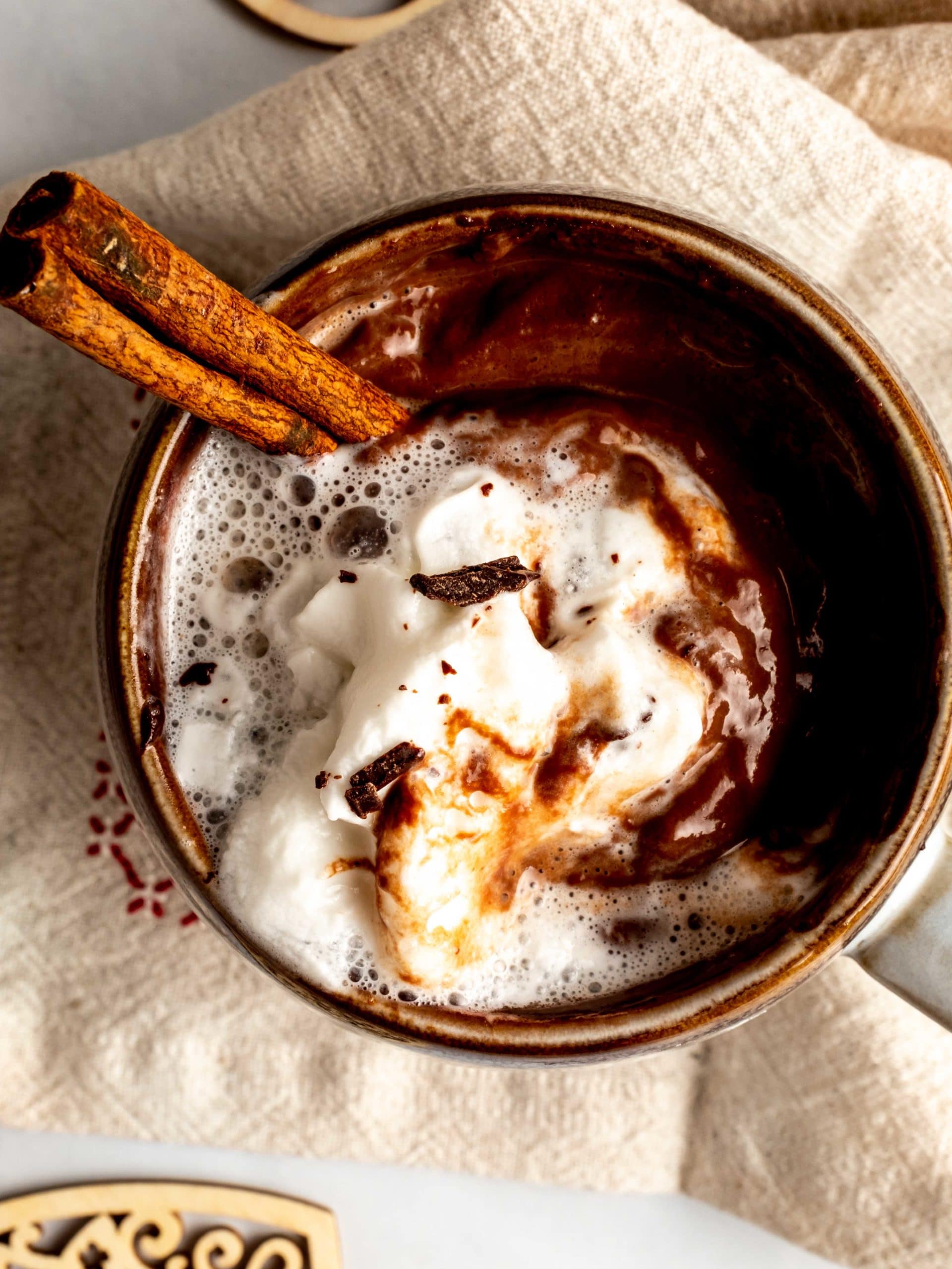 overhead view of espresso sipping chocolate with whipped cream and cinnamon stick