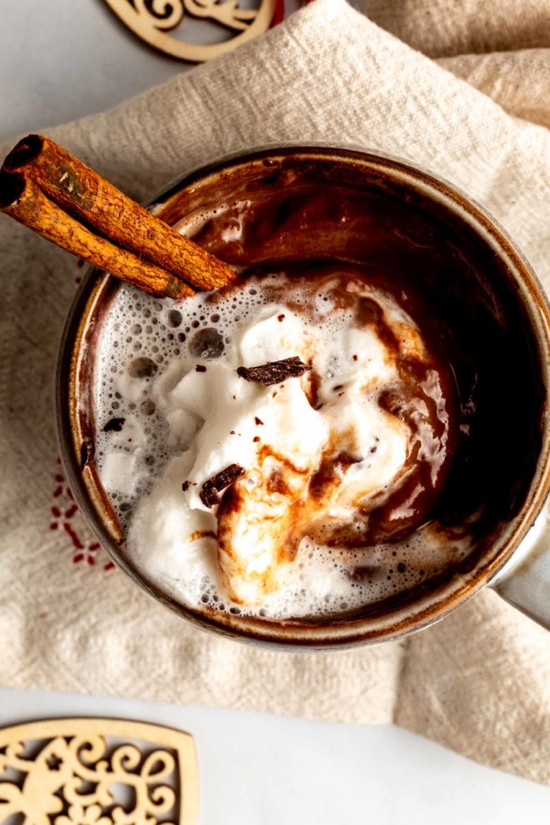 overhead view of espresso sipping chocolate with whipped cream and cinnamon stick