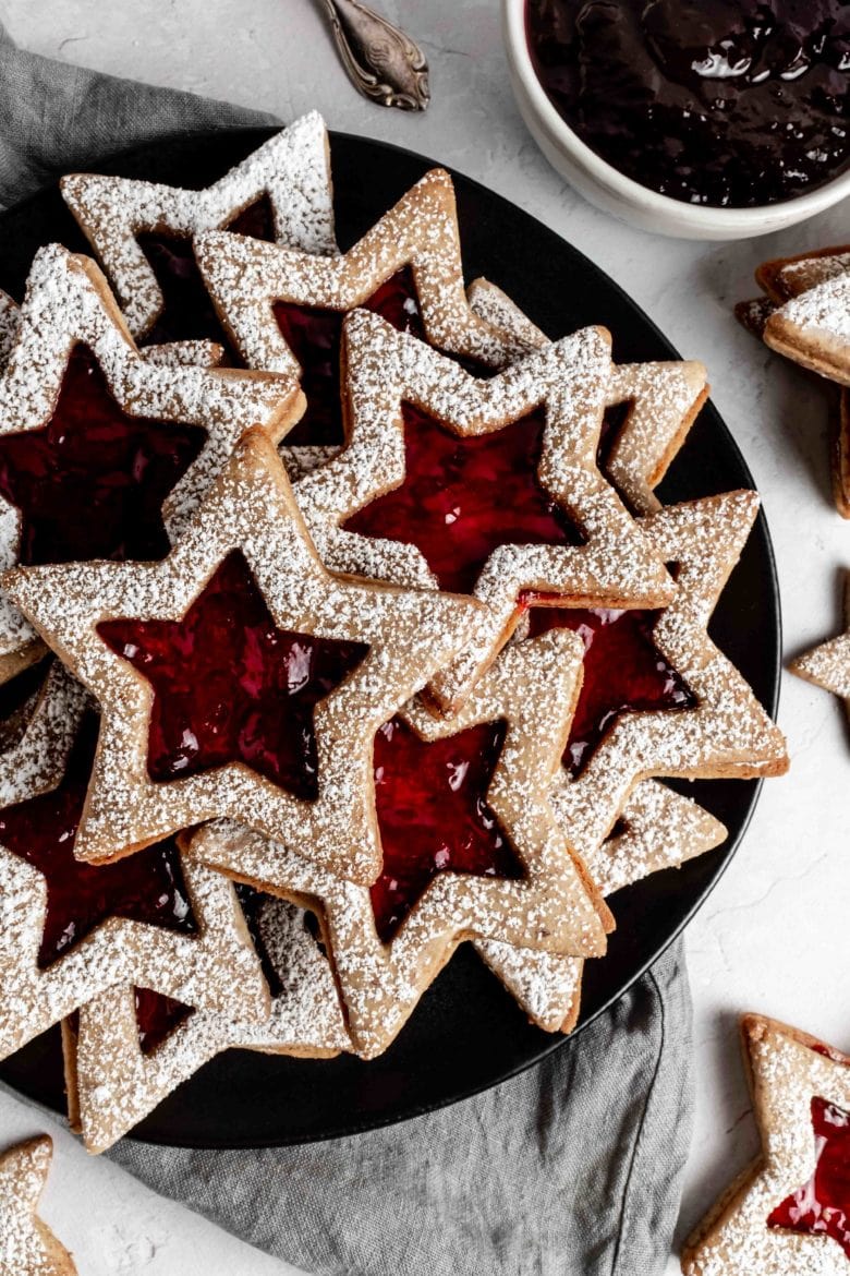 linzer cookies with wine jelly dusted with powdered sugar on a plate
