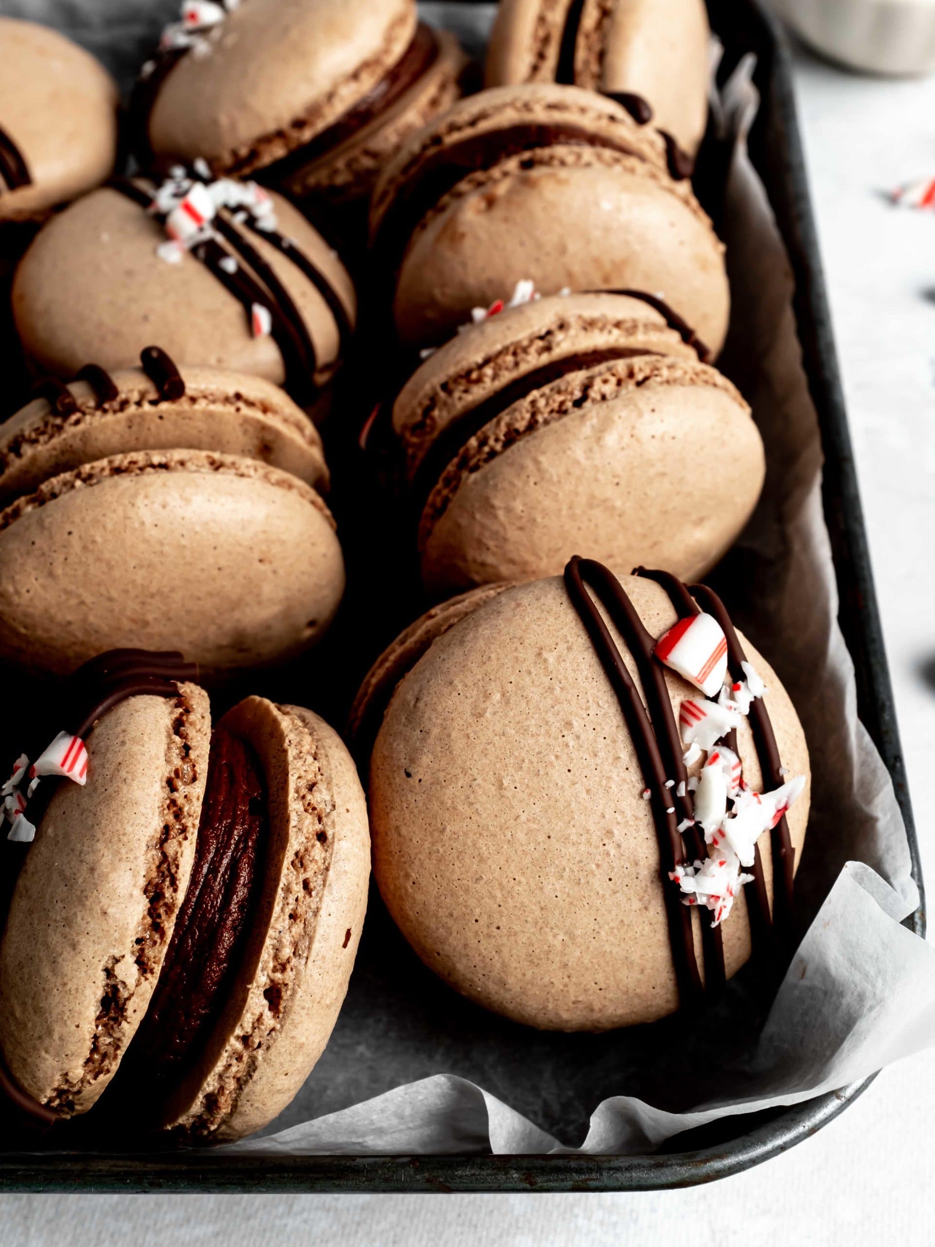 tin of macarons with chocolate drizzle and crushed peppermint