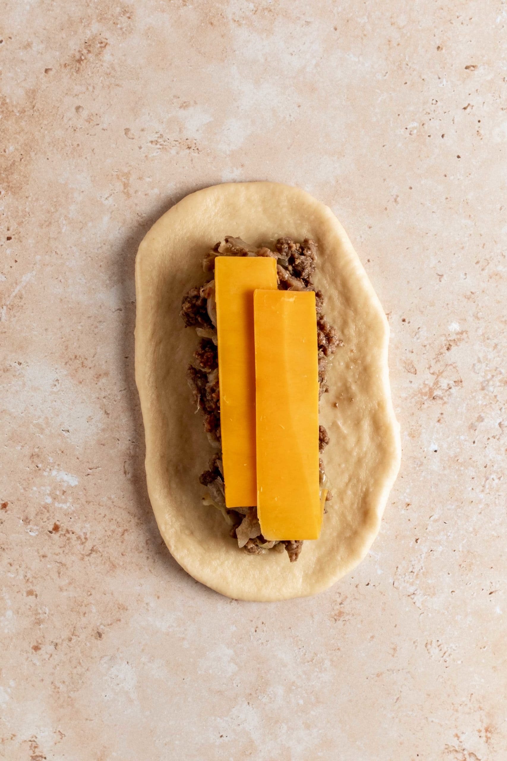 rolled out dough with beef, cabbage and cheese