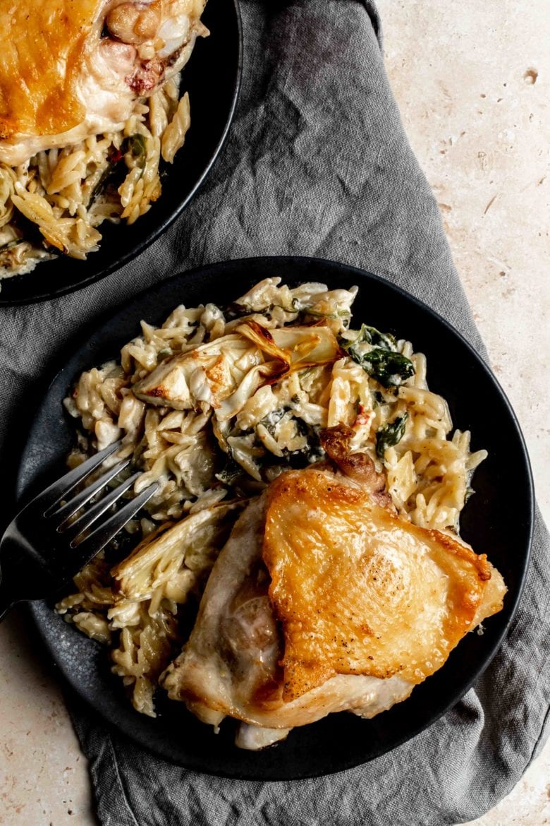 plate with crispy chicken thigh and creamy spinach artichoke orzo