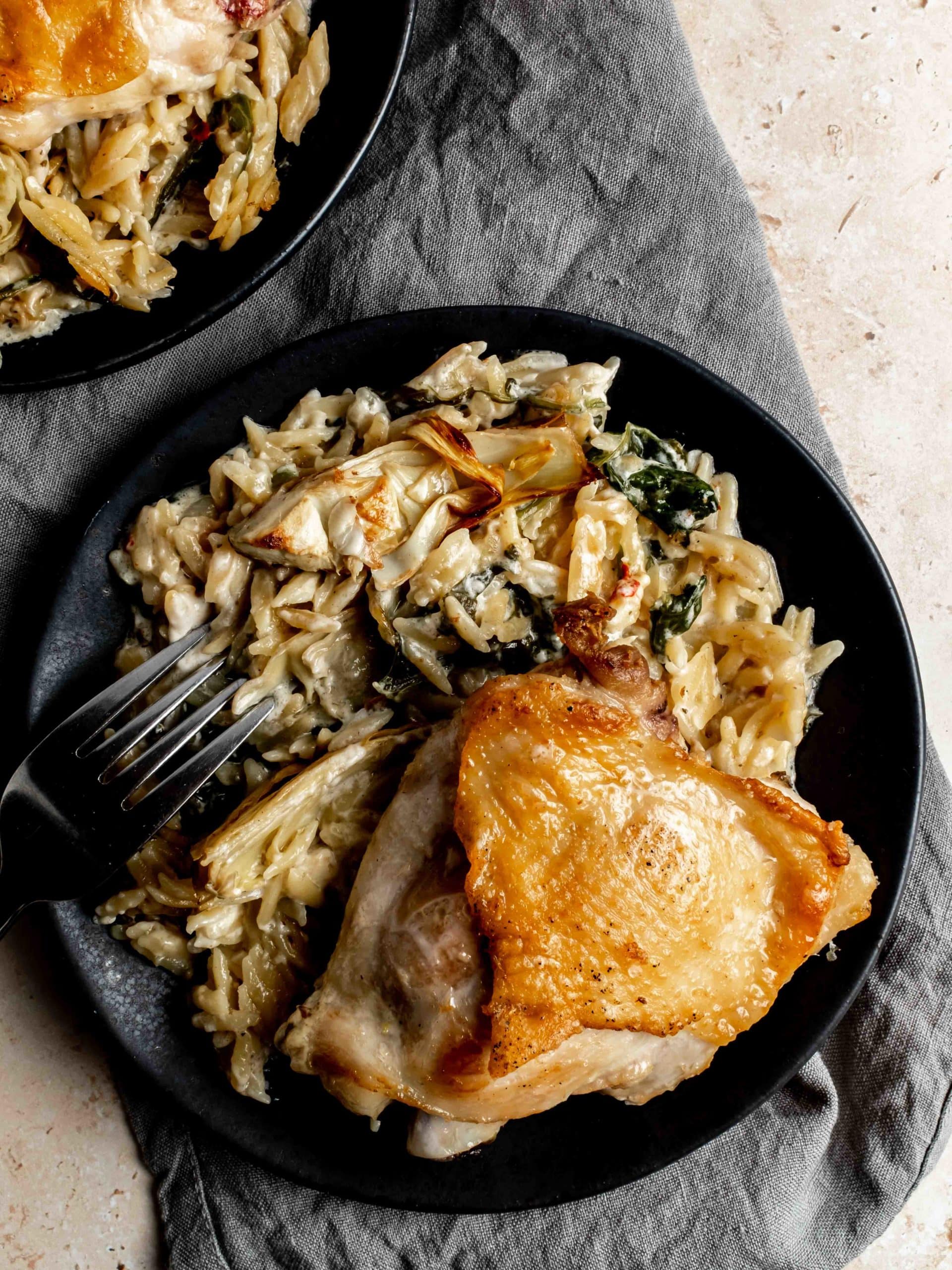 plate with crispy chicken thigh and creamy spinach artichoke orzo