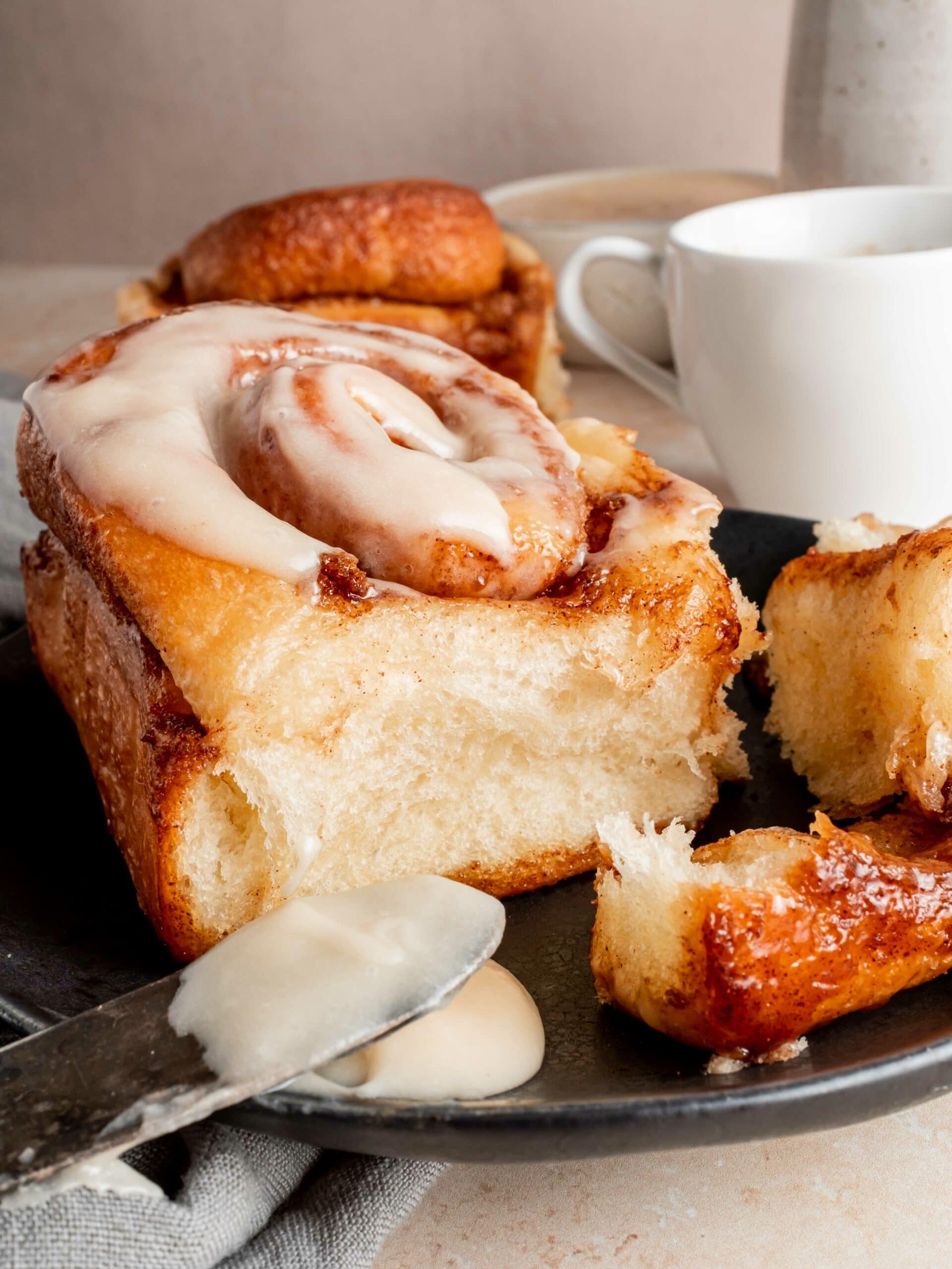 cinnamon roll on plate with frosting and coffee