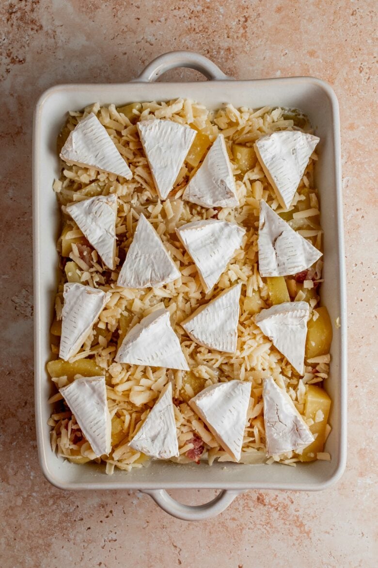 potatoes in baking dish topped with gruyere and camembert