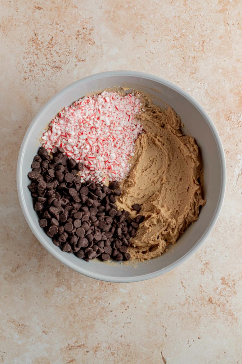 adding chocolate chips and crushed candy cane to the cookie dough