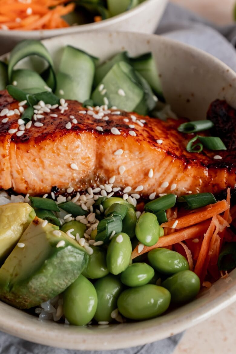broiled salmon over sushi rice with edamame, avocado, carrots and cucumber