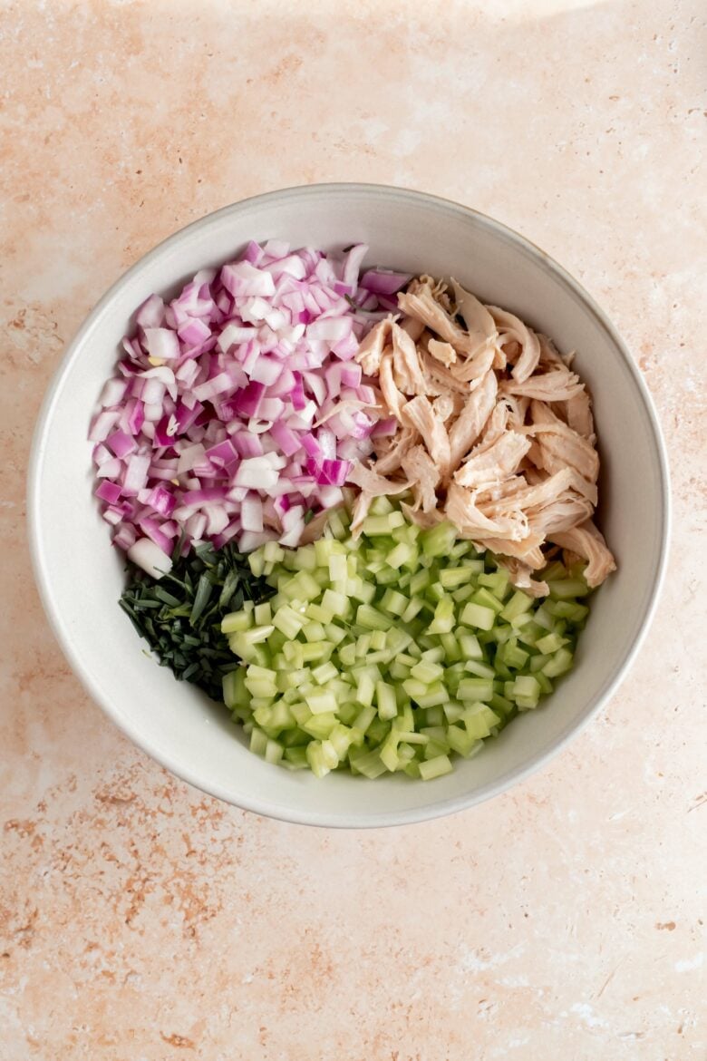 shredded chicken, red onion, celery and tarragon in a bowl before mixing