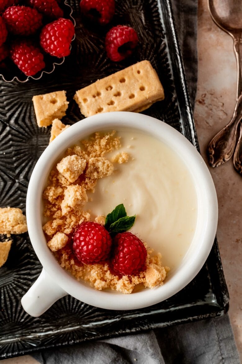 cup with lemon posset and topped with shortbread crumbs, raspberries and mint