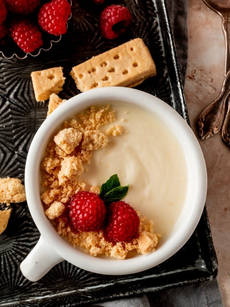 cup with lemon posset and topped with shortbread crumbs, raspberries and mint