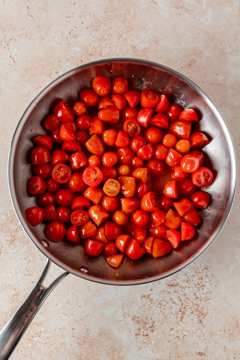 halved grape tomatoes in a skillet with olive oil