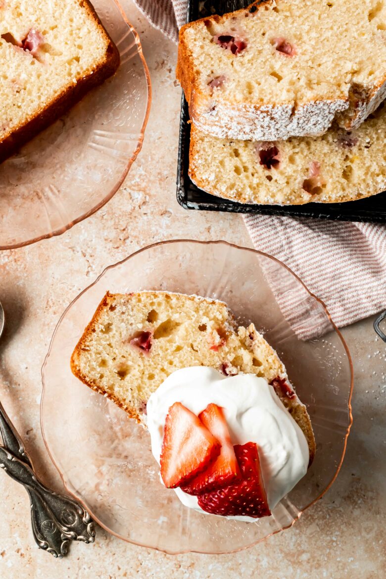 slice of pound cake on a plate with whipped cream and fresh strawberries