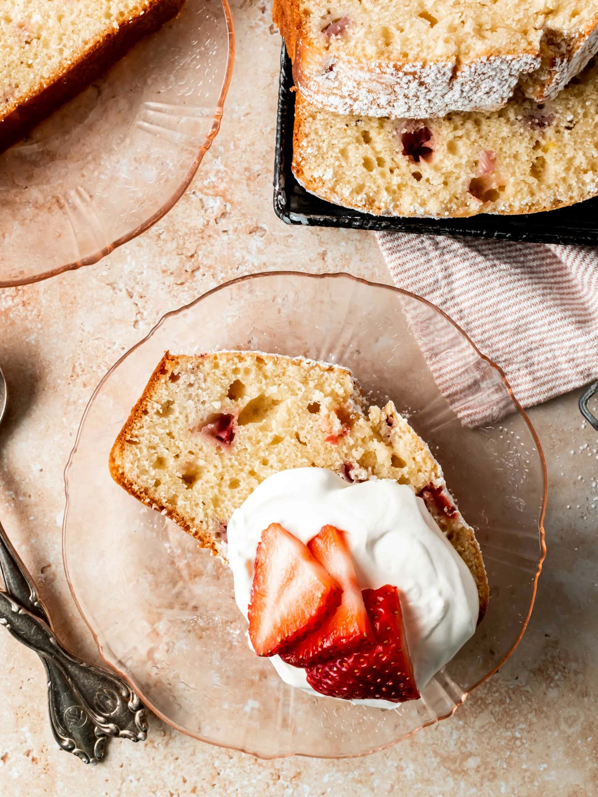 slice of pound cake on a plate with whipped cream and fresh strawberries