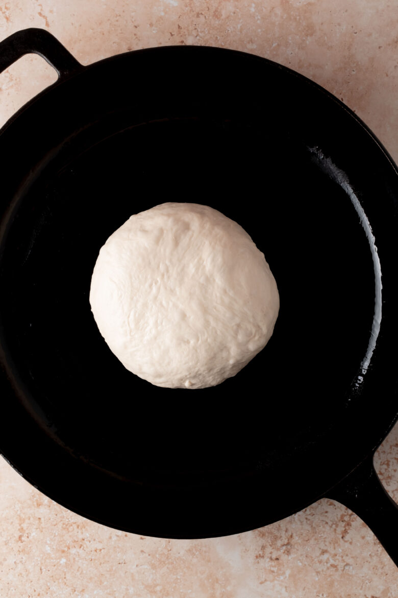 Ball of pizza dough in cast iron skillet