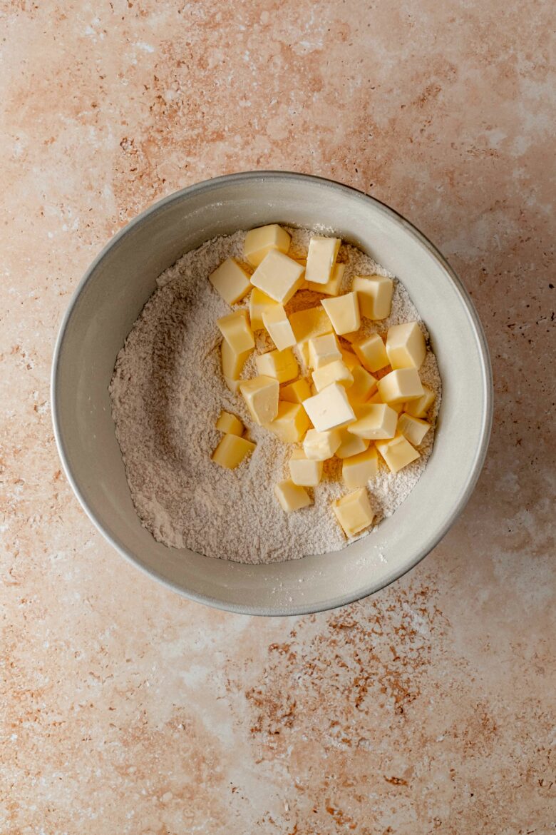 cubed butter in bowl with flour, sugar, baking powder and salt