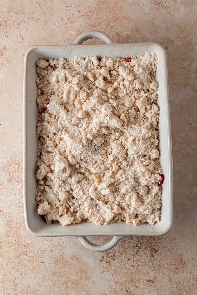 crumble sprinkled over strawberries in baking dish