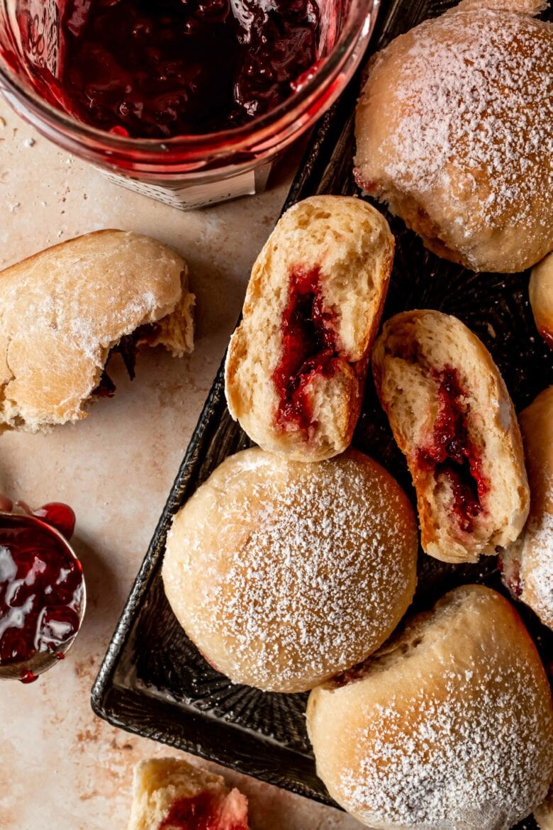 buchty sprinkled with powdered sugar on a platter with cherry preserves