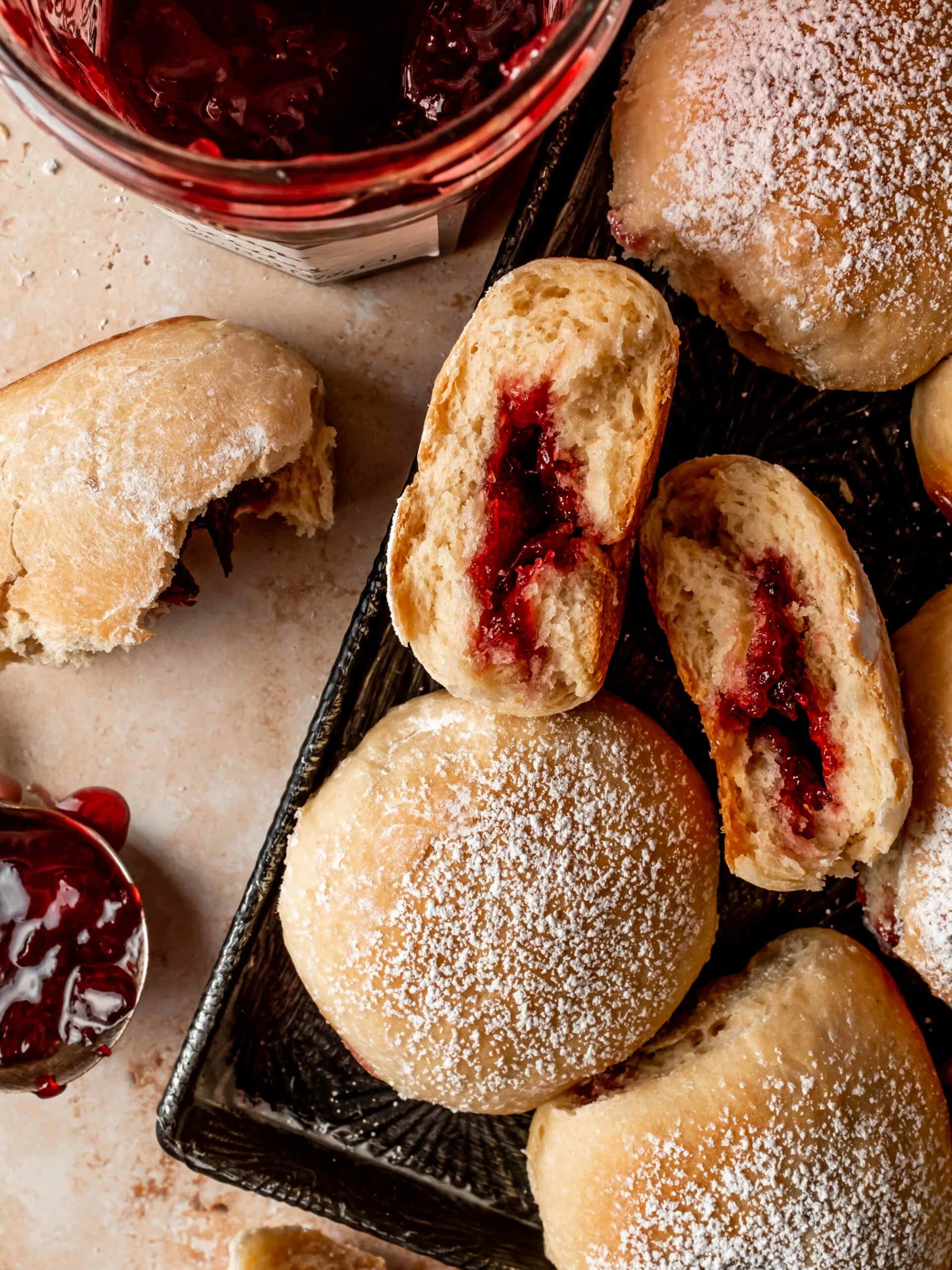 buchty sprinkled with powdered sugar on a platter with cherry preserves