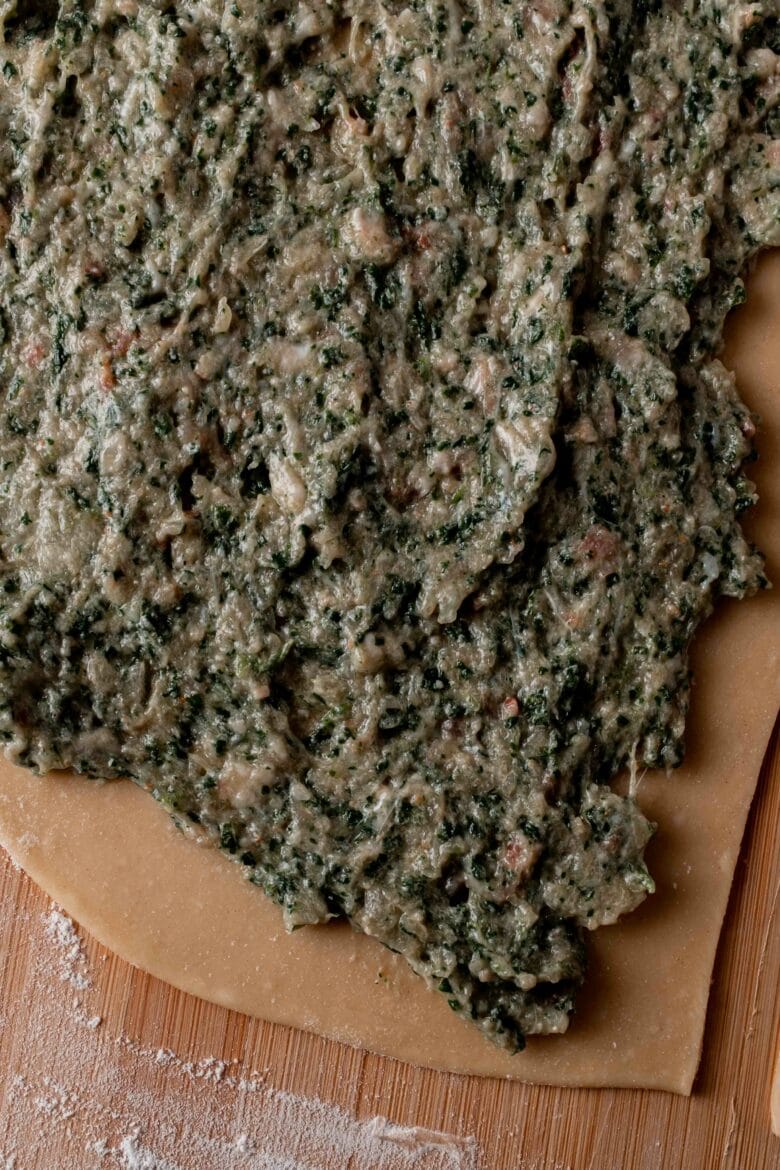 close up of spinach and meat filling spread onto dough