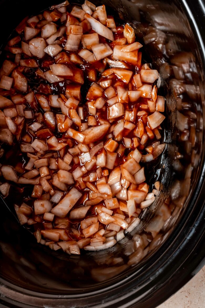 Barbecue sauce, apple cider vinegar and diced onions in the bowl of a slow cooker