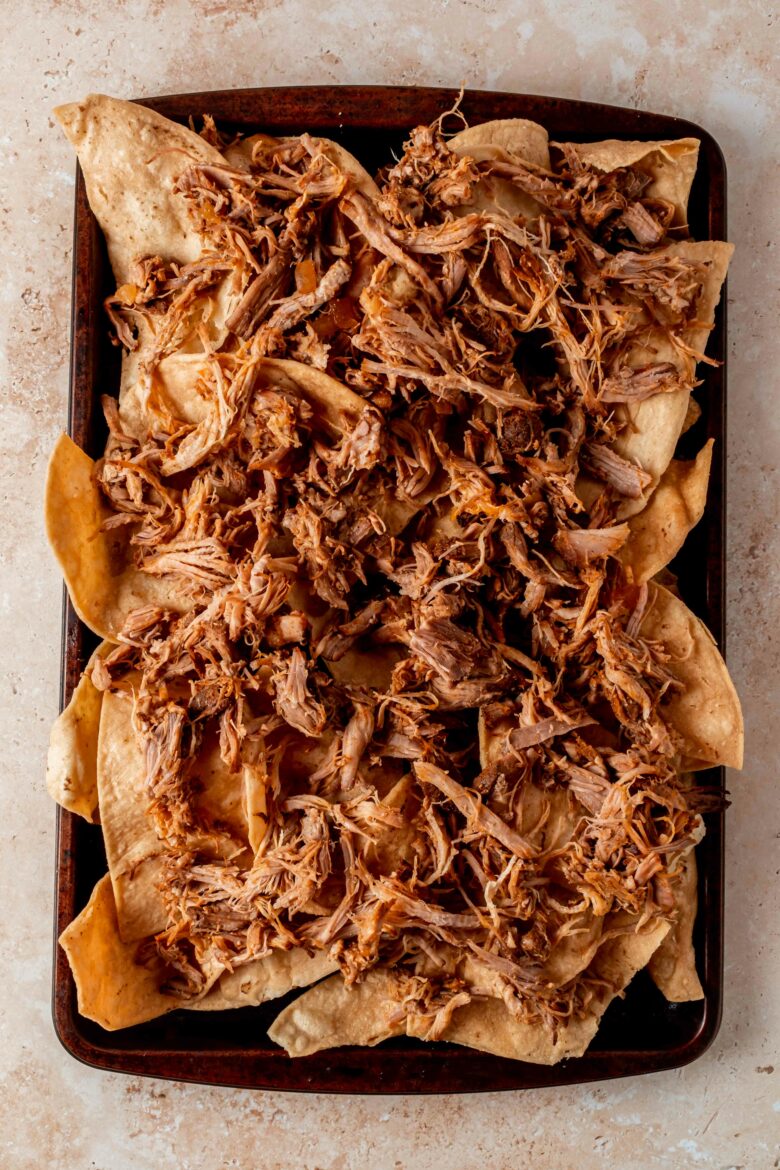 Adding pulled pork to the tortilla chips